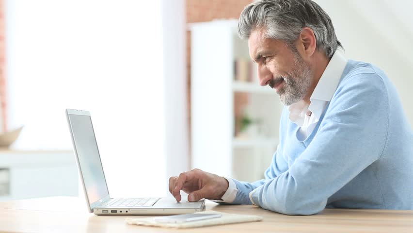 Homem sentado usando um laptop - crédito consignado para abrir um negócio