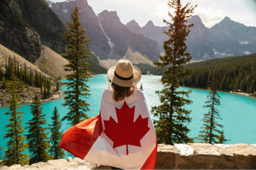 mulher usando a bandeira do canadá admirando a paisagem para representar o seguro viagem canadá