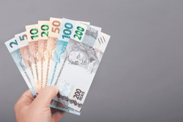 mão segurando notas de real para representar como funciona a antecipação de salário