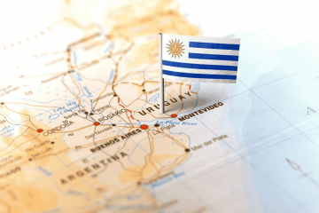 mapa e bandeira do uruguai representando o seguro viagem para o uruguai